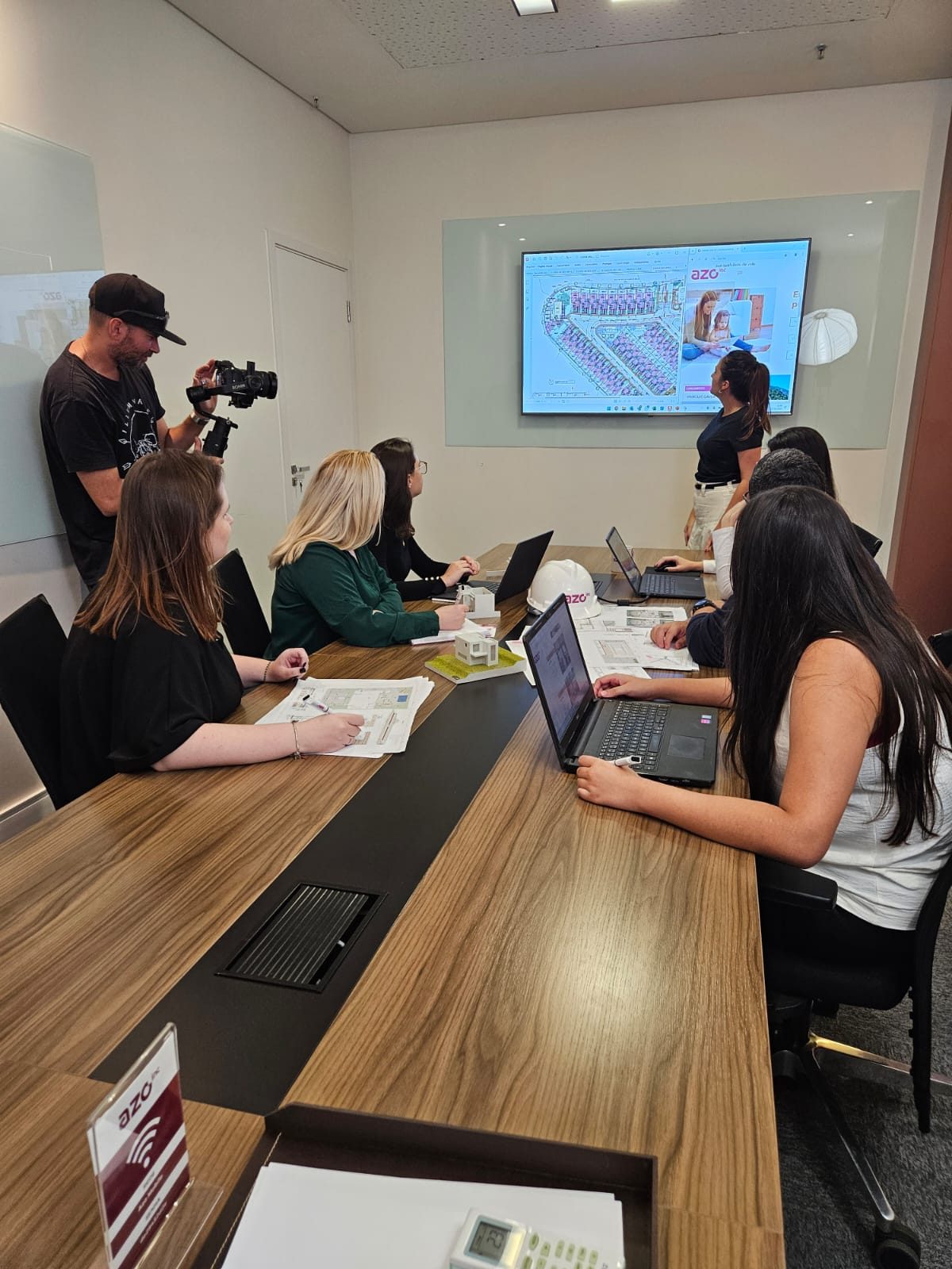 Treinamento de produto com equipe comercial em sala de reunião, com implantação do empreendimento na tela
